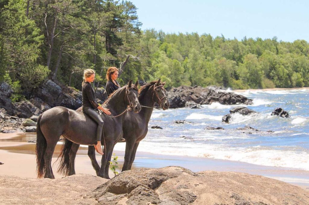 2-friesian-horses-riders-on-the-beach